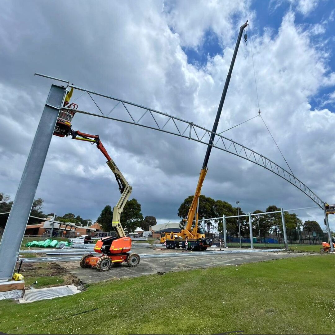 Industrial rigging for high school COLA construction at Ambervale, lifting steel framework with cranes and access equipment.