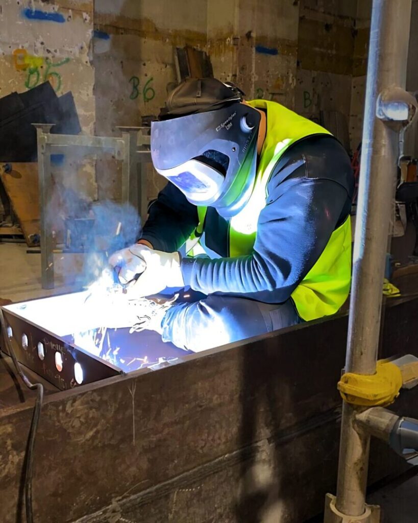 Boilermaker welding inside a steel structure during onsite fabrication at an industrial project