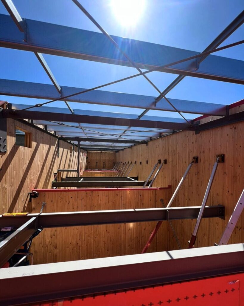 Interior view of steel beams installed between timber walls under the sun at a Warriewood construction site.